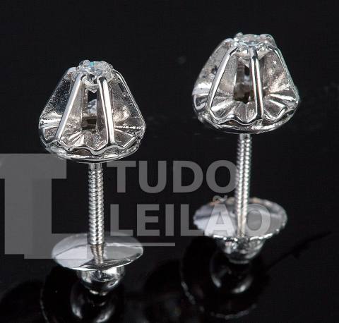 Brinco solitário em ouro branco 18k, com dois diamantes totalizando aproximadamente 0,16 ct, purezas: VVS e SI. Cor aproximada: G/H
